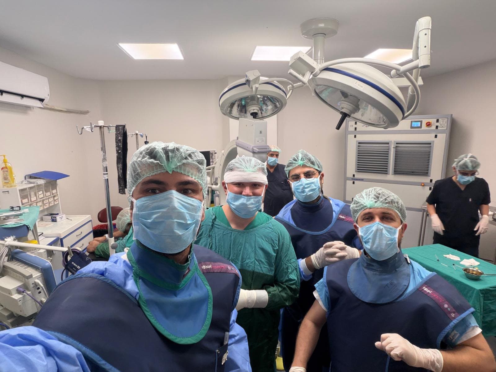 Ameliyathanede maske ve koruyucu ekipmanlarıyla poz veren sağlık ekibi.